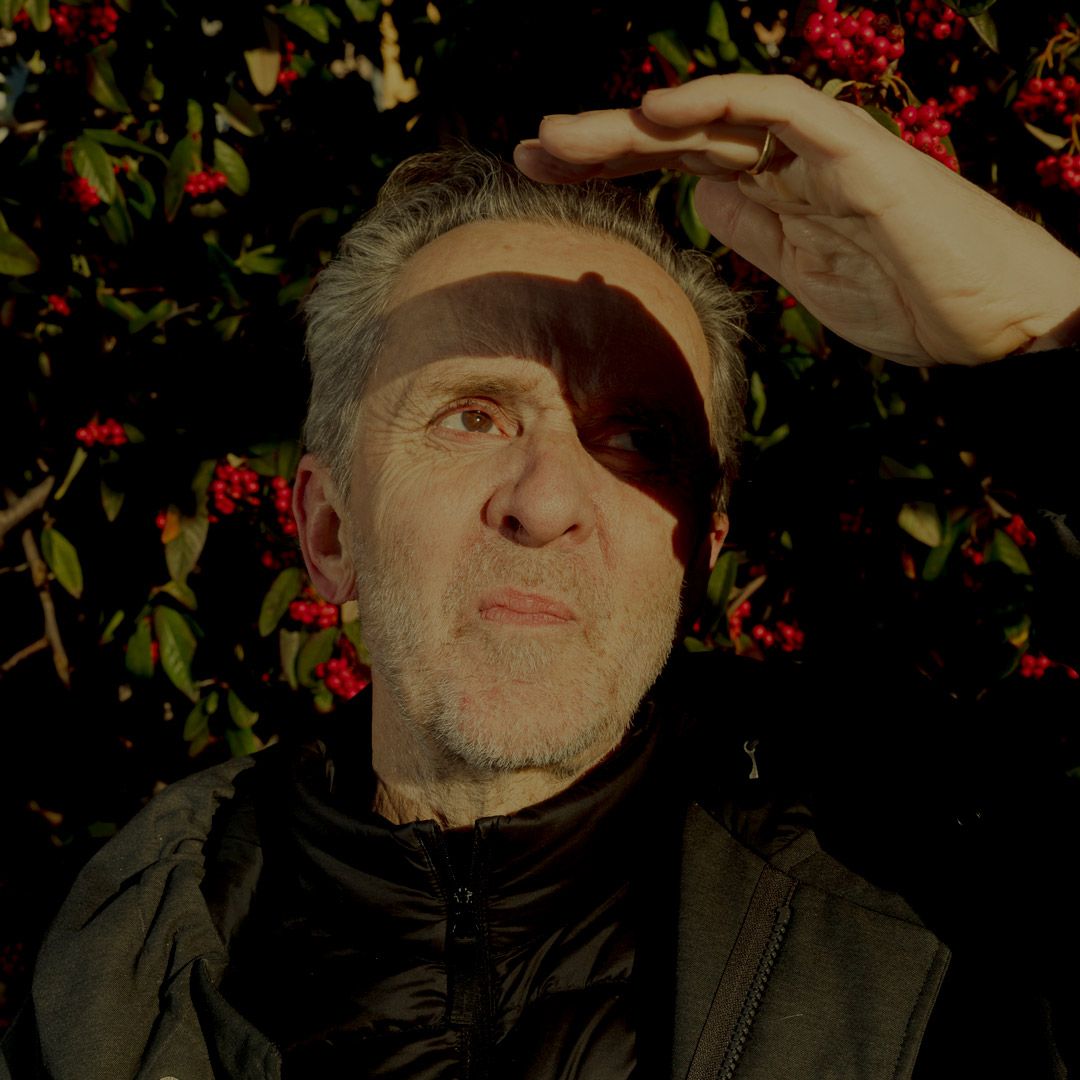 Kim Fupz tager hånden op for at skygge for solen foran en busk med røde bær.