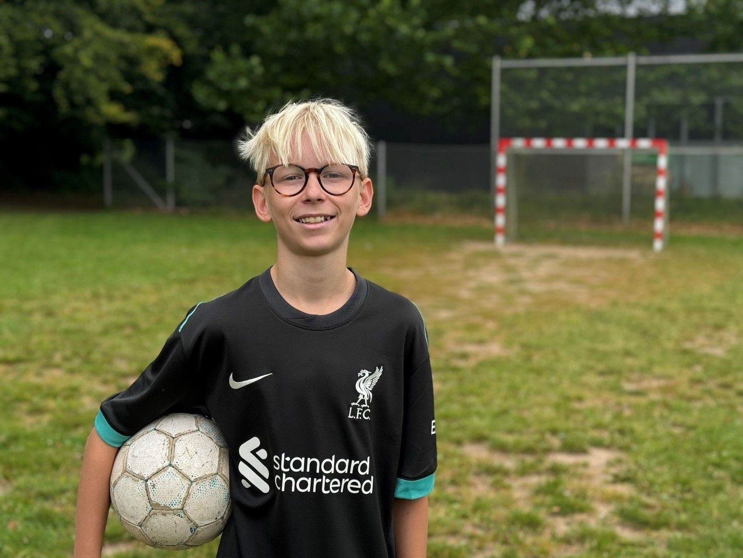 Et billede af elev p&aring; fodboldbane med fodbold under armen