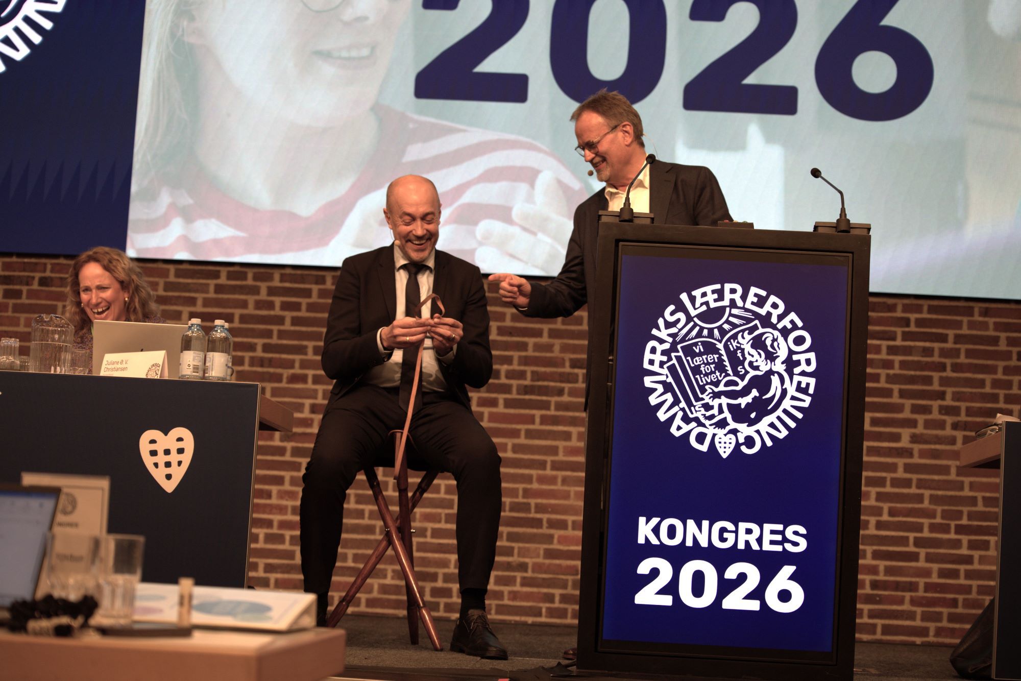 Magnus Heunicke sidder p&aring; skammel p&aring; scenen til kongres. Gordon &Oslash;rskov Madsen st&aring;r ved siden af