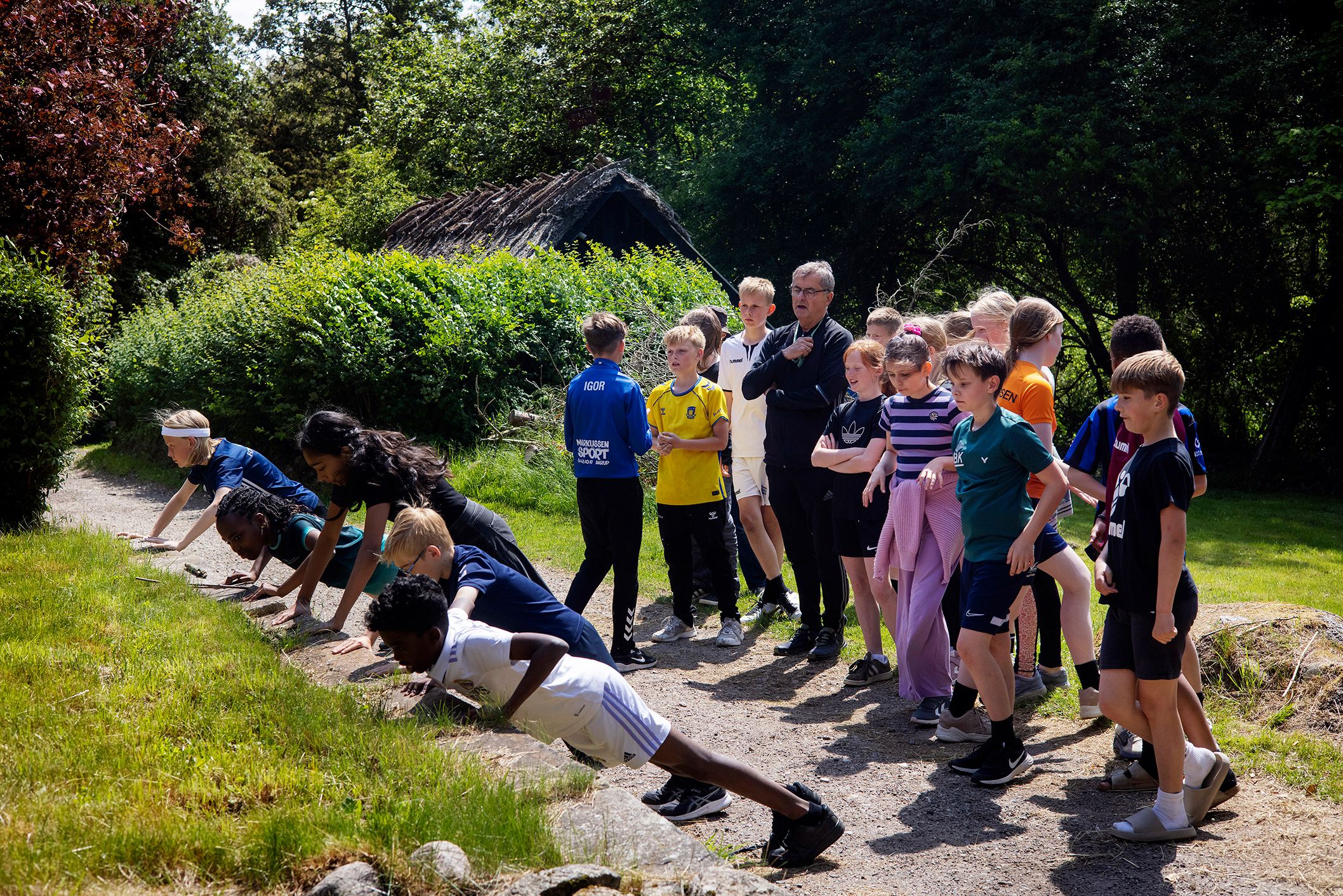 Billede af Ole Nielsen og hans elever i gang med undervisningen, hvor nogle er i gang med en planke&oslash;velse.