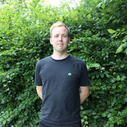 Mads Viuff Davidsen i mørk t-shirt foran en hæk