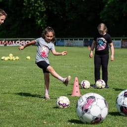 Dreng i 8. klasse instruerer piger på mellemtrinnet i fodbold
