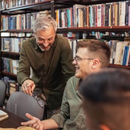 Erfaren lærer taler med studerende eller ung lærer på bibliotek