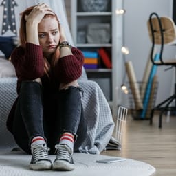 Trist teenagepige sidder på gulvet i sit værelse