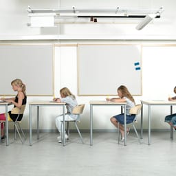 Fire elever ved skoleborde på række