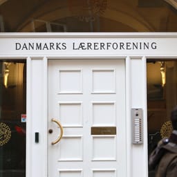 Indgang til Danmarks Lærerforenings domicil - hvid dør med navnet i messingbogstaver, mand går forbi