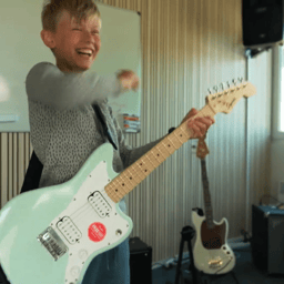 dreng spiller guitar i øvecontainer