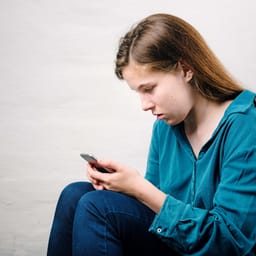 Trist pige sidder med sin mobil