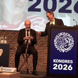 Magnus Heunicke sidder på skammel på scenen til kongres. Gordon Ørskov Madsen står ved siden af
