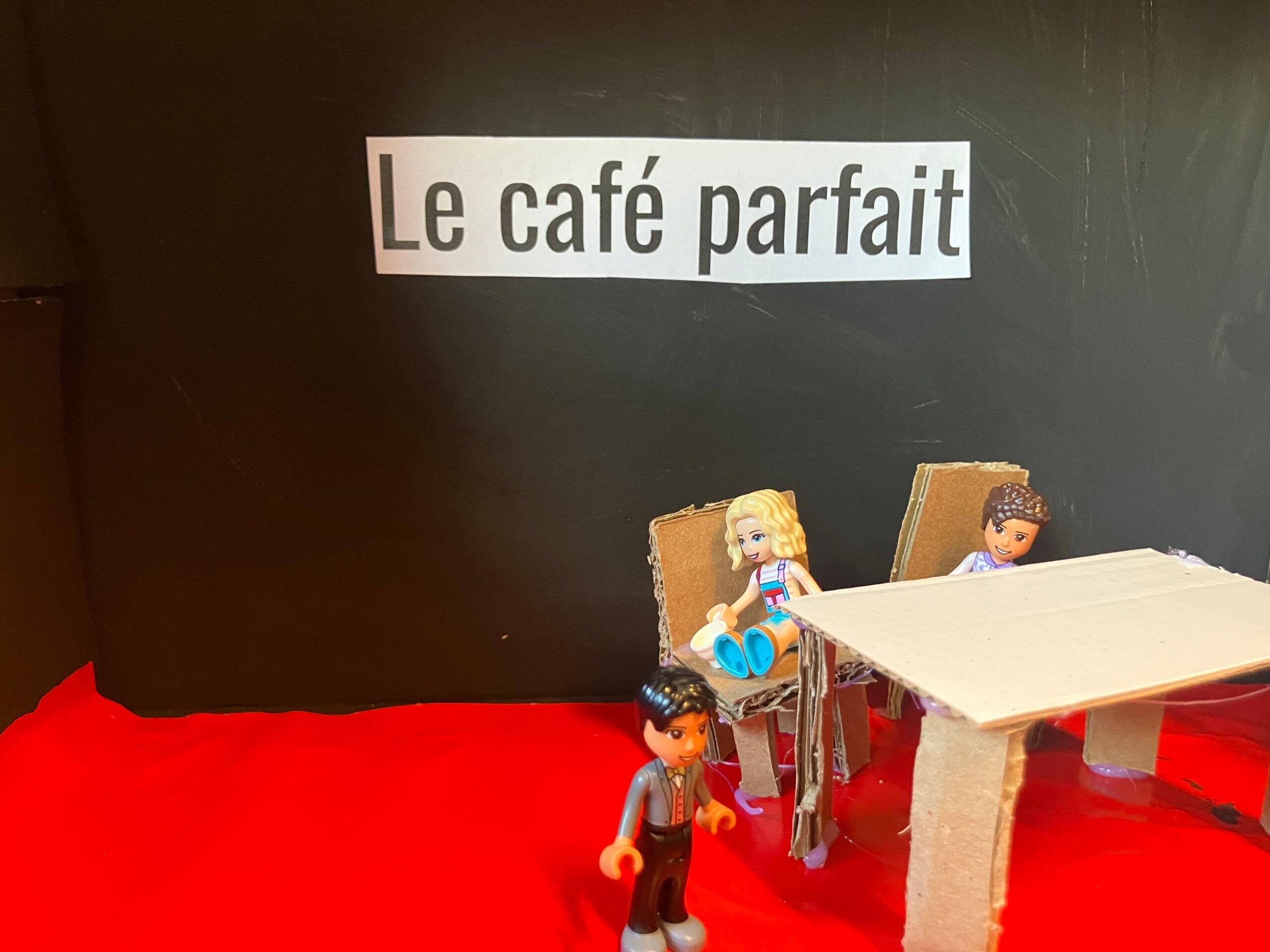 Billede af Stop Motion filmproduktionen. Billedet viser sm&aring; papfigurer, der sidder p&aring; en cafe.