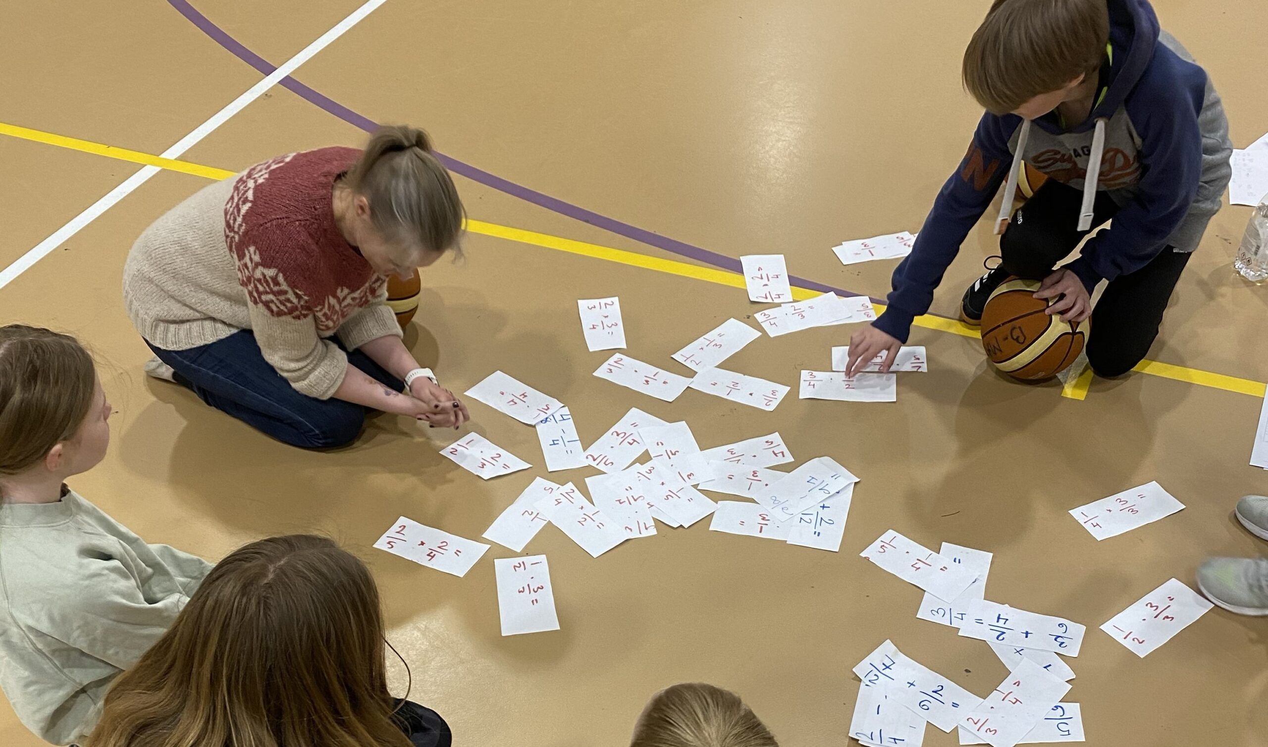 Lærer og elever løser brøkopgaver på et halgulv