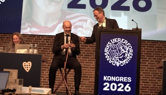 Magnus Heunicke sidder på skammel på scenen til kongres. Gordon Ørskov Madsen står ved siden af