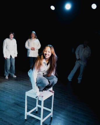 Billede af en pige der står på en skammel på scenen og er i gang med at fremvise forestillingen