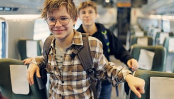 To teenagedrenge i et tog. De smiler