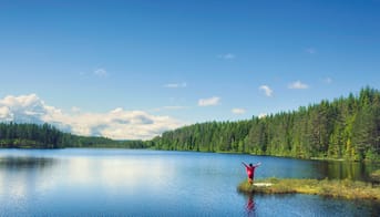 Kvinde hilser på solskin og sommer ved en sø