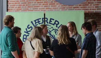 Gruppe af lærerstuderende samlet foran banner med Danmarks Lærerforenings logo
