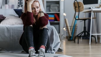 Trist teenagepige sidder på gulvet i sit værelse