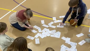 Lærer og elever løser brøkopgaver på et halgulv