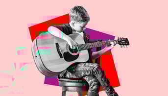 Dreng i 4. eller 5. klasse spiller guitar med benene over kors.