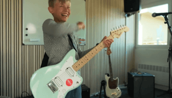 dreng spiller guitar i øvecontainer