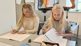 Billede af to elever der sidder ved et bord og er i gang med at løse en opgave