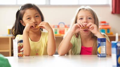 To små piger spiser mad i et klasselokale