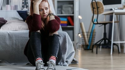 Trist teenagepige sidder på gulvet i sit værelse
