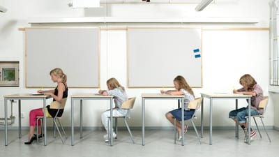Fire elever ved skoleborde på række